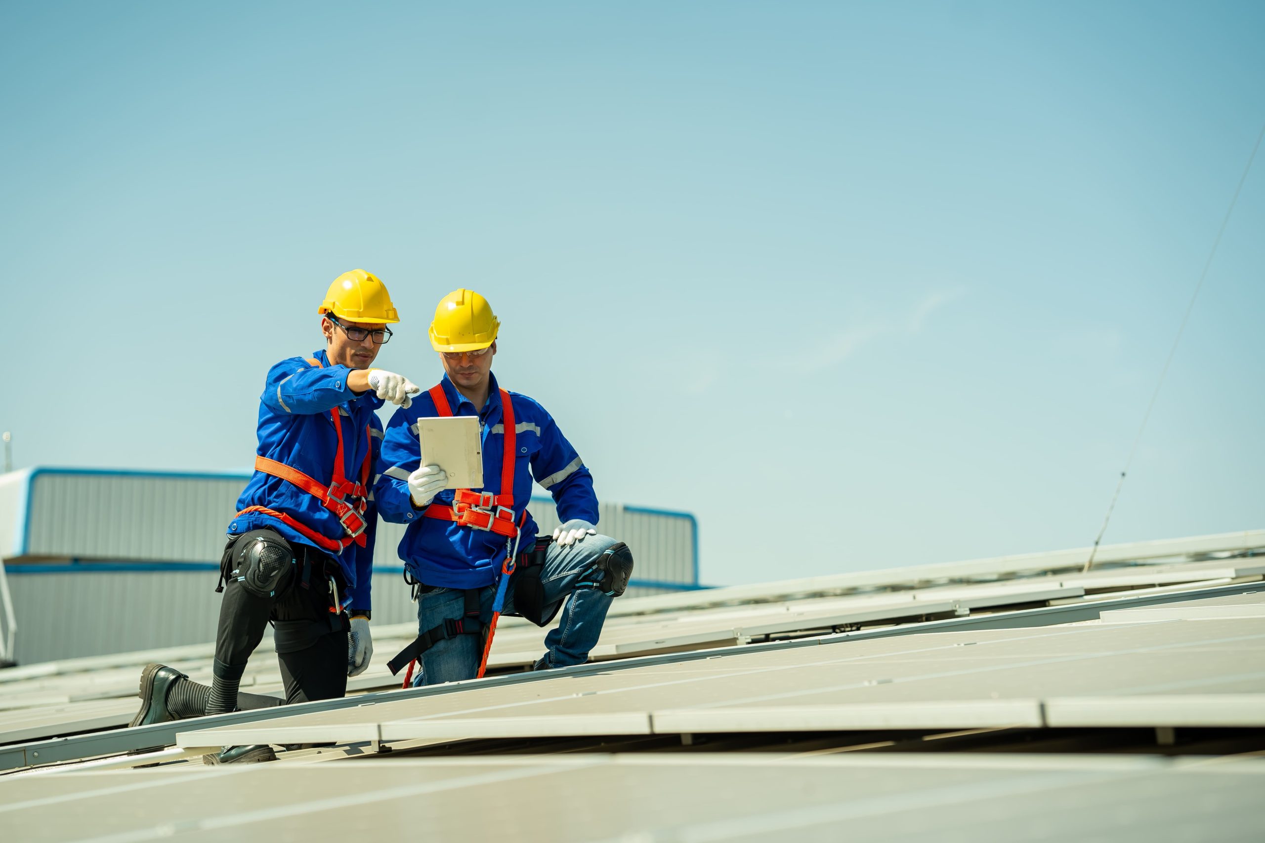Two roofing inspectors review tablet data on a commercial roof in Reno